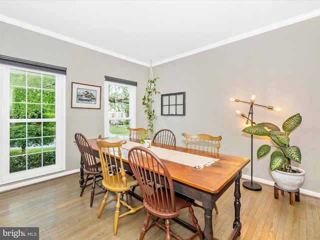 dining area featuring light wood finished floors, ornamental molding, and baseboards