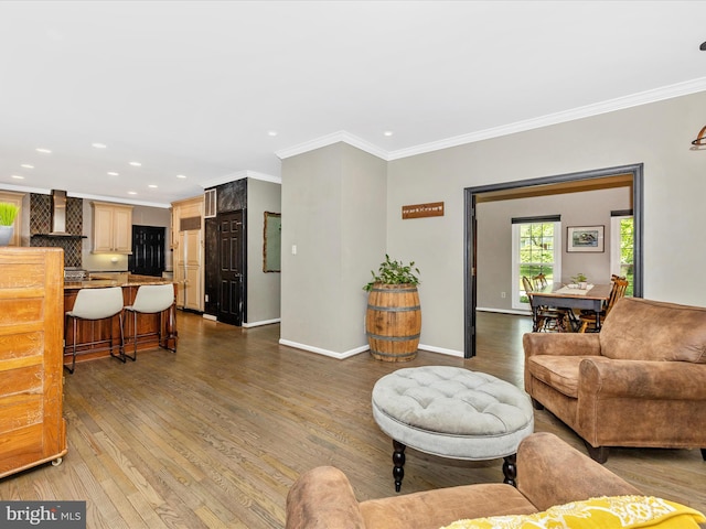 living area with recessed lighting, wood finished floors, ornamental molding, and baseboards