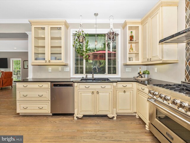 kitchen featuring cream cabinets, stainless steel appliances, a sink, dark countertops, and ornamental molding
