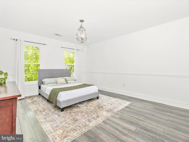 bedroom with wood finished floors, a chandelier, and baseboards