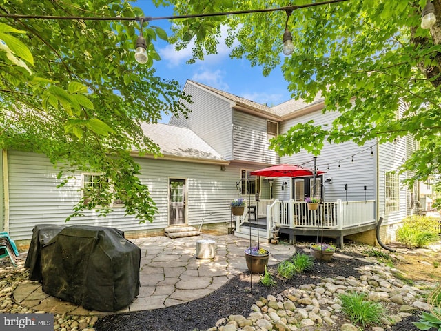 back of house featuring a wooden deck, a patio area, and roof with shingles