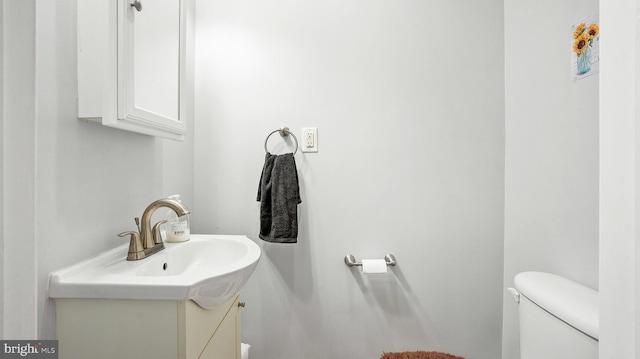 half bathroom featuring vanity and toilet