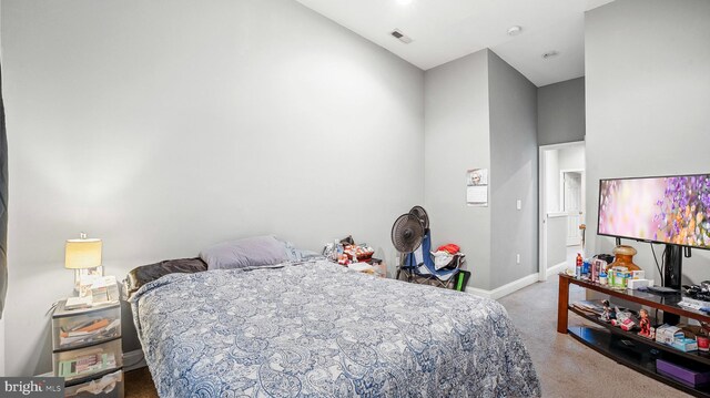 carpeted bedroom with baseboards, visible vents, and a high ceiling