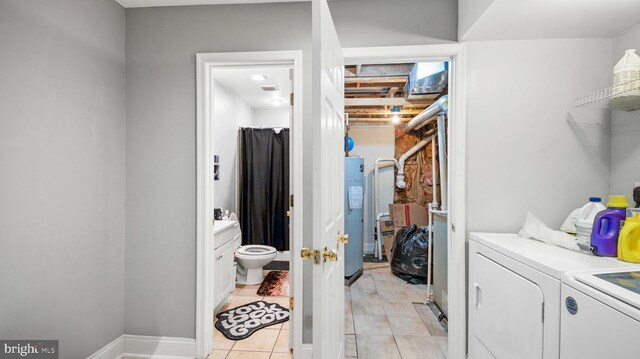 clothes washing area featuring separate washer and dryer, light tile patterned floors, water heater, baseboards, and laundry area