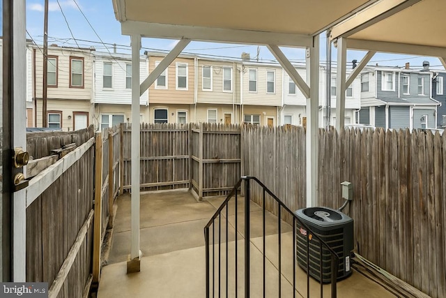 view of patio / terrace featuring a residential view, central AC unit, and fence