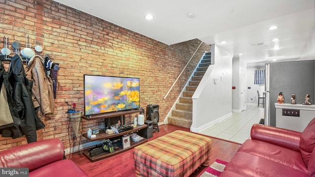 living area featuring recessed lighting, wood finished floors, baseboards, stairs, and brick wall