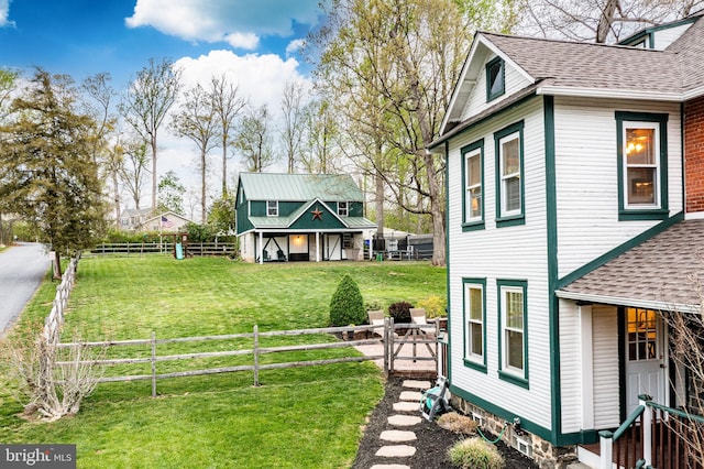 view of property exterior with a yard, fence private yard, and roof with shingles