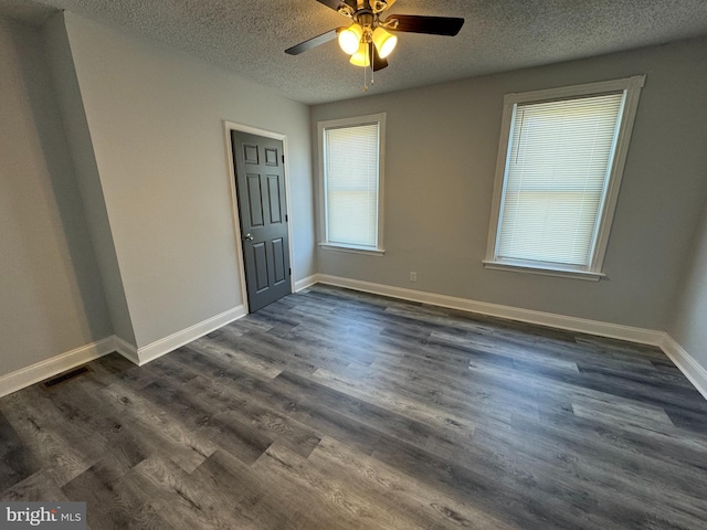 spare room with a textured ceiling, ceiling fan, baseboards, dark wood-style flooring, and visible vents