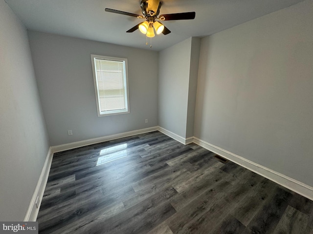 unfurnished room featuring dark wood finished floors, a ceiling fan, and baseboards