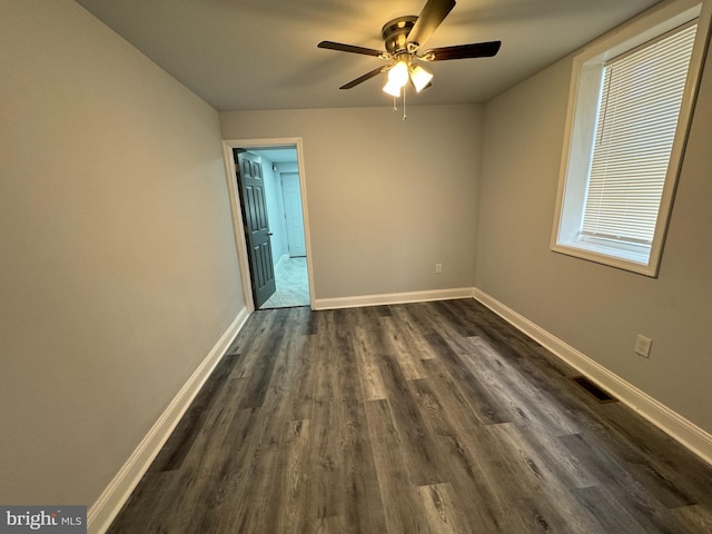 spare room with a ceiling fan, baseboards, dark wood-style flooring, and visible vents