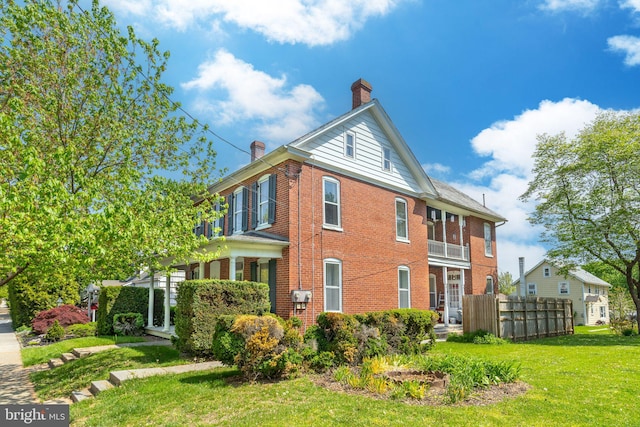 view of property exterior with brick siding, a chimney, and a lawn
