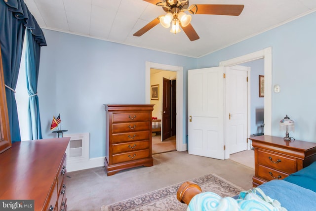 carpeted bedroom with crown molding, baseboards, a ceiling fan, and visible vents