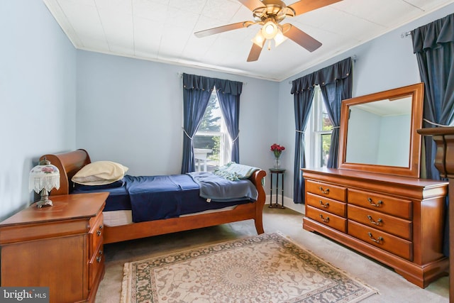 carpeted bedroom featuring crown molding and ceiling fan