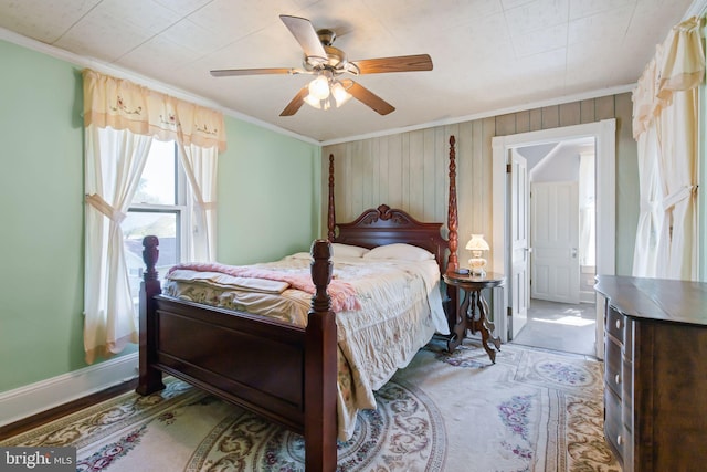 bedroom featuring crown molding, wood walls, baseboards, and a ceiling fan