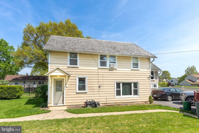 view of front of house featuring fence, a front lawn, and cooling unit
