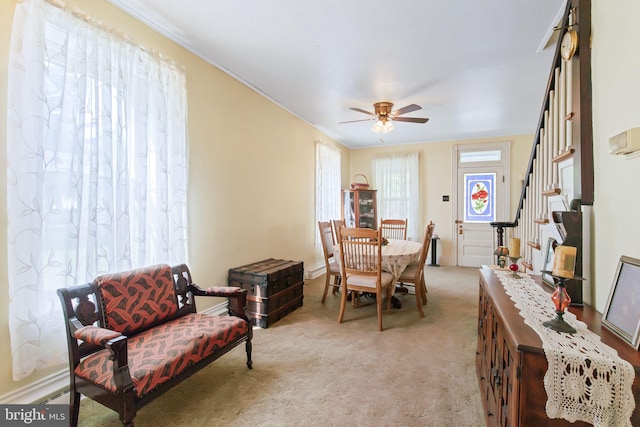 sitting room featuring stairway, ceiling fan, light carpet, crown molding, and baseboards