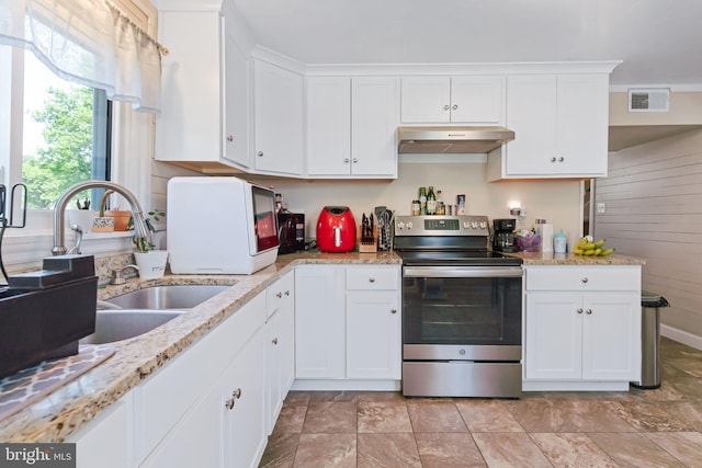 kitchen featuring stainless steel range with electric stovetop, stone finish flooring, white cabinetry, visible vents, and under cabinet range hood