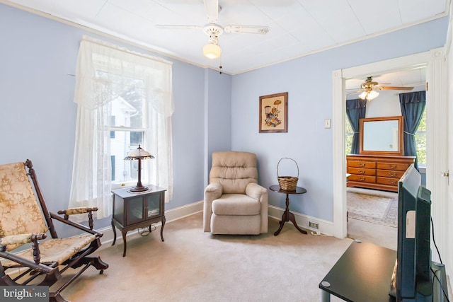 sitting room featuring carpet flooring, crown molding, baseboards, and a ceiling fan