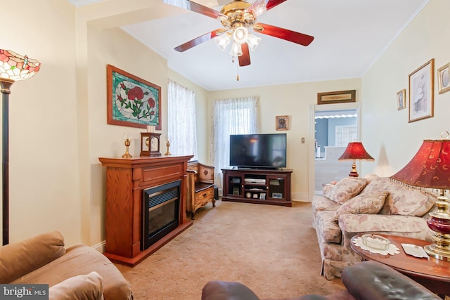 living area with light carpet, baseboards, a ceiling fan, and a glass covered fireplace