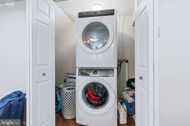 laundry room featuring laundry area, stacked washer and clothes dryer, and wood finished floors