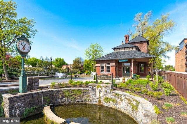 rear view of property featuring fence and a garden pond