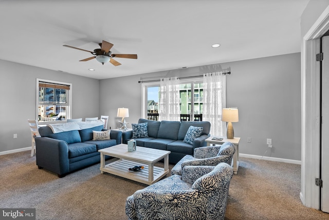 living area featuring a healthy amount of sunlight, baseboards, a ceiling fan, and carpet flooring
