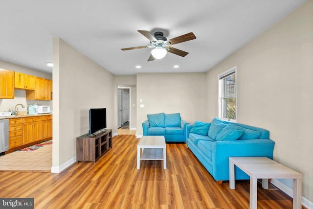living area featuring a ceiling fan, baseboards, recessed lighting, and light wood-style floors