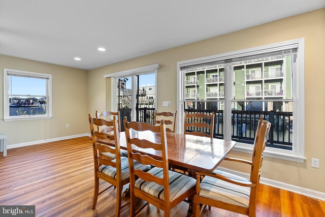 dining room featuring baseboards, recessed lighting, wood finished floors, and a healthy amount of sunlight