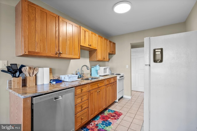 kitchen featuring a sink, light stone counters, white appliances, and light tile patterned flooring