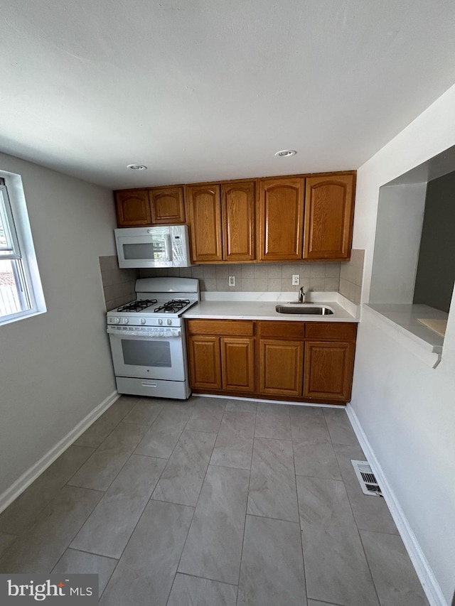 3086 Cedar St, Philadelphia, PA 19134 - kitchen with a sink, backsplash, white appliances, brown cabinets, and light countertops