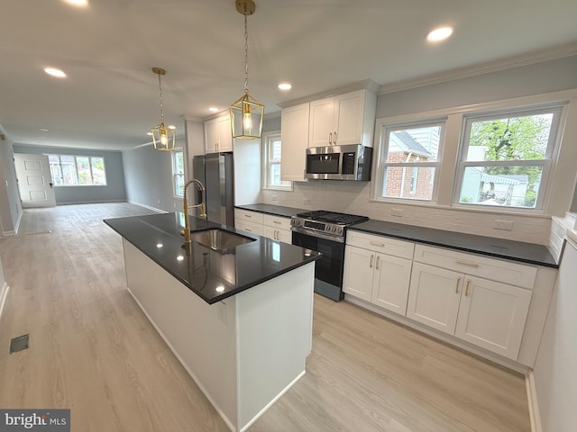 kitchen with crown molding, dark countertops, a sink, light wood-style floors, and stainless steel appliances