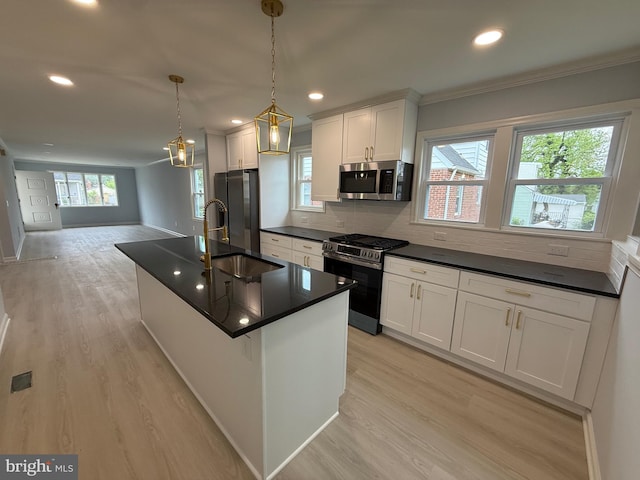 kitchen featuring ornamental molding, dark countertops, a sink, light wood-style flooring, and stainless steel appliances