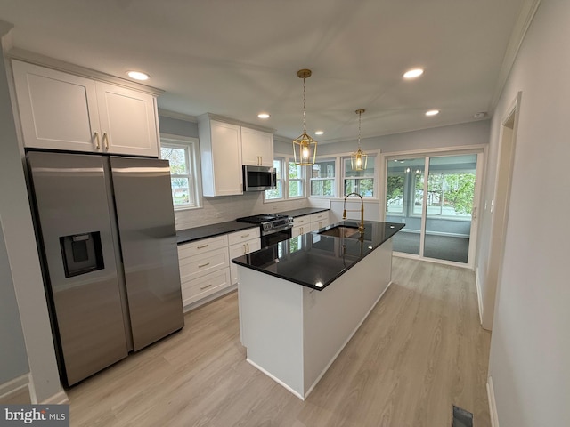kitchen with dark countertops, a sink, light wood finished floors, stainless steel appliances, and white cabinetry