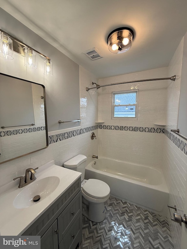 full bathroom featuring visible vents, tile walls, bathtub / shower combination, vanity, and toilet