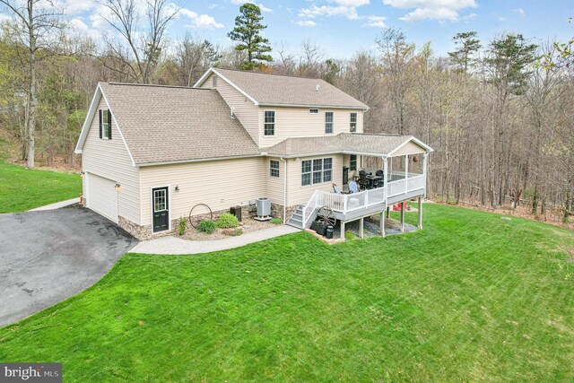 back of property with a wooden deck, a yard, central air condition unit, and roof with shingles