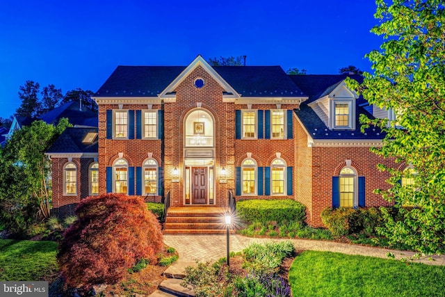 colonial inspired home featuring brick siding and a shingled roof