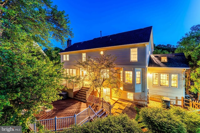 back of property featuring fence, a chimney, a shingled roof, and stairway