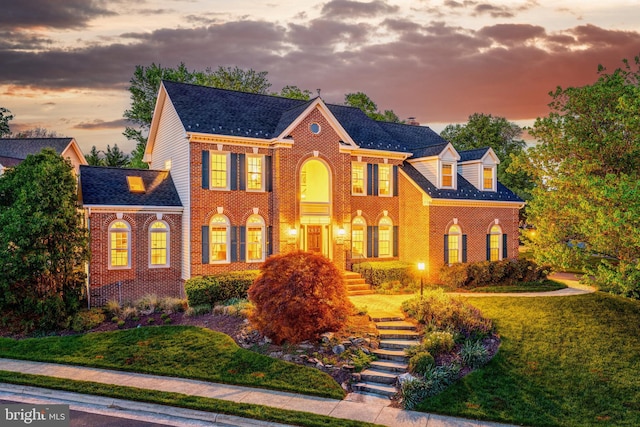 colonial home with brick siding and a shingled roof