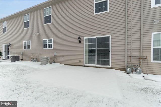 snow covered rear of property with cooling unit