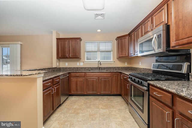 kitchen with a peninsula, appliances with stainless steel finishes, a sink, and plenty of natural light