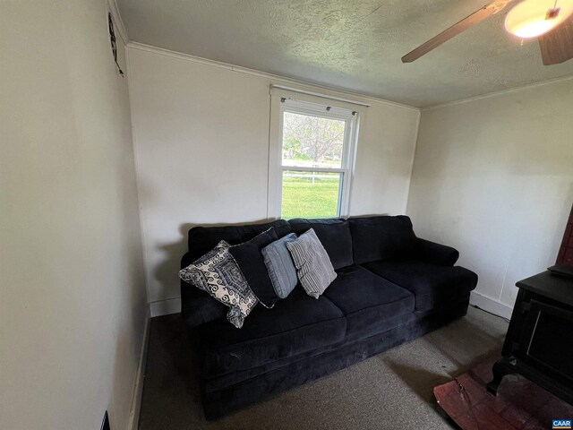 living room featuring baseboards, ceiling fan, carpet, and a textured ceiling