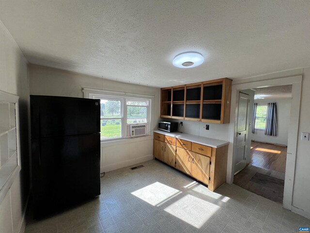 kitchen featuring plenty of natural light, freestanding refrigerator, stainless steel microwave, and visible vents