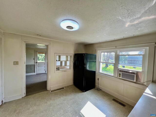 kitchen featuring freestanding refrigerator, a textured ceiling, baseboards, and visible vents