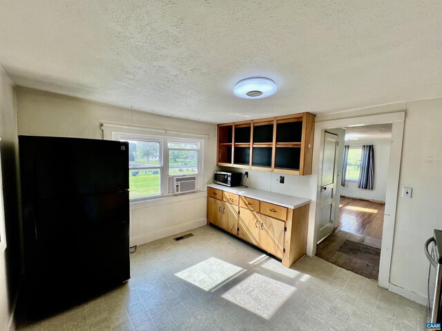 kitchen with appliances with stainless steel finishes, light countertops, a textured ceiling, light floors, and visible vents