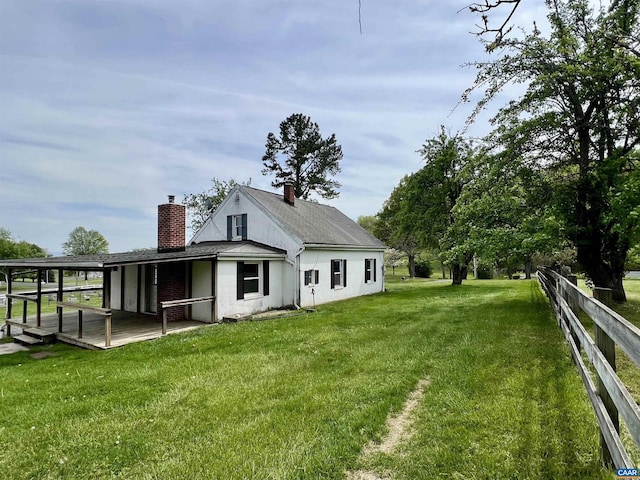 rear view of house with a wooden deck, a yard, a chimney, and fence