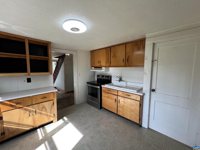 kitchen with light countertops, brown cabinetry, electric range, and a sink