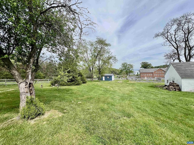 view of yard with a storage shed, fence, and an outbuilding