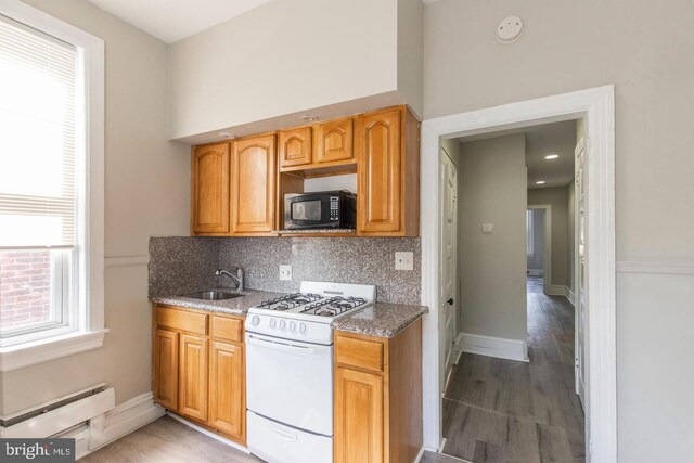 3547 N 21st St, Philadelphia, PA 19140 - kitchen with a baseboard heating unit, light wood finished floors, a sink, white gas range oven, and black microwave