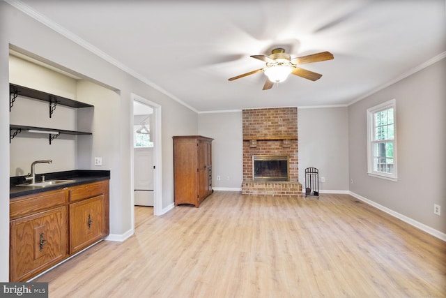 unfurnished living room with healthy amount of natural light, a ceiling fan, light wood finished floors, a fireplace, and crown molding