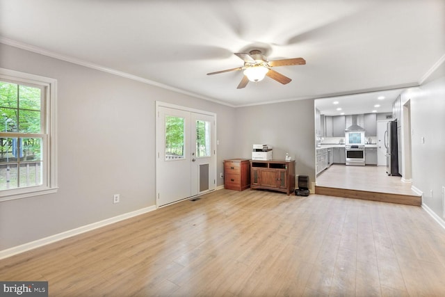 unfurnished living room with a ceiling fan, ornamental molding, baseboards, healthy amount of natural light, and light wood-type flooring